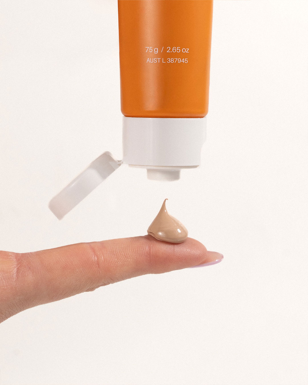 Squeezing Mineral Pro Tinted Sunscreen on a finger